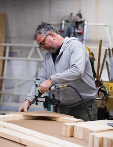 Engraphix Custom Carpenter working on wood signs with staple gun