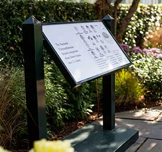 Interpretive sign at New York Garden, black and white with flowers around it
