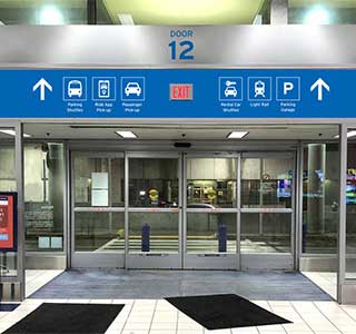 Airport wayfinding directional signs above elevator in blue and white