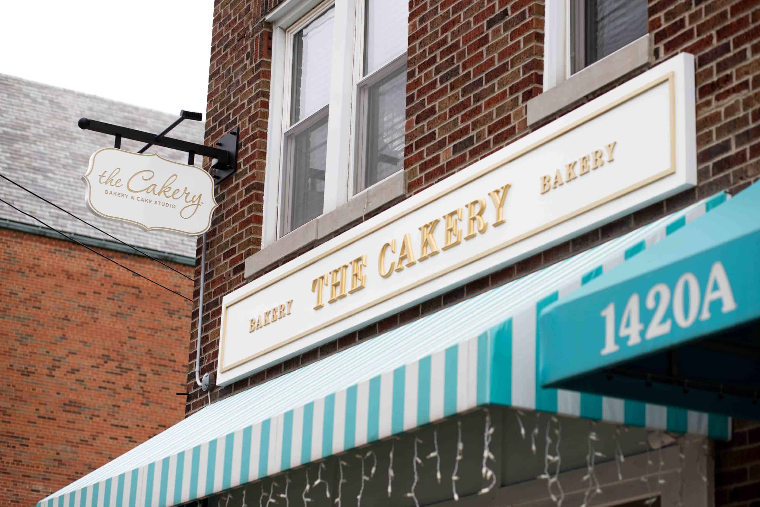 Exterior bakery panel sign on brick in white and gold