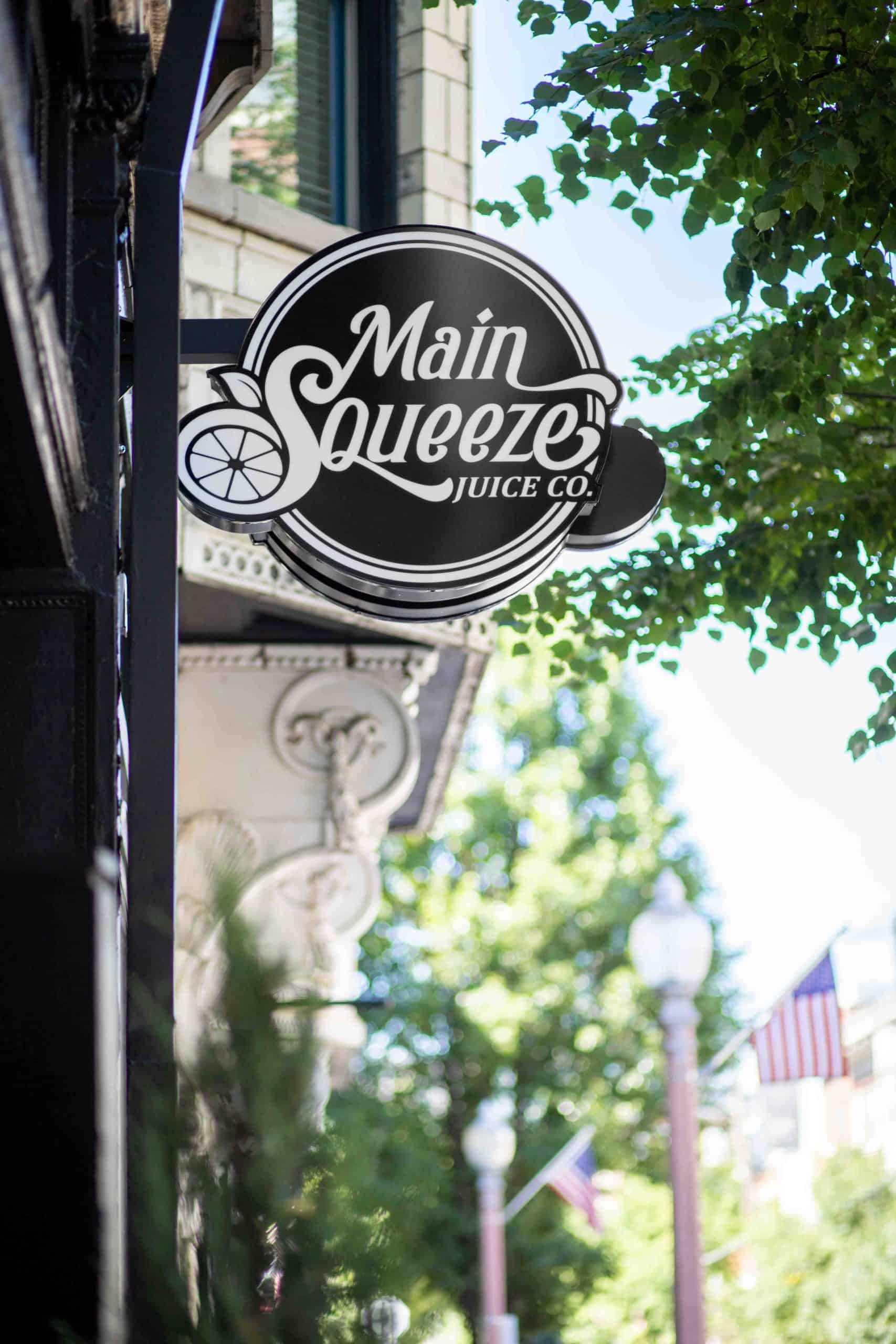 Main Squeeze Juice Co Blade Sign with Tree leaves Framing