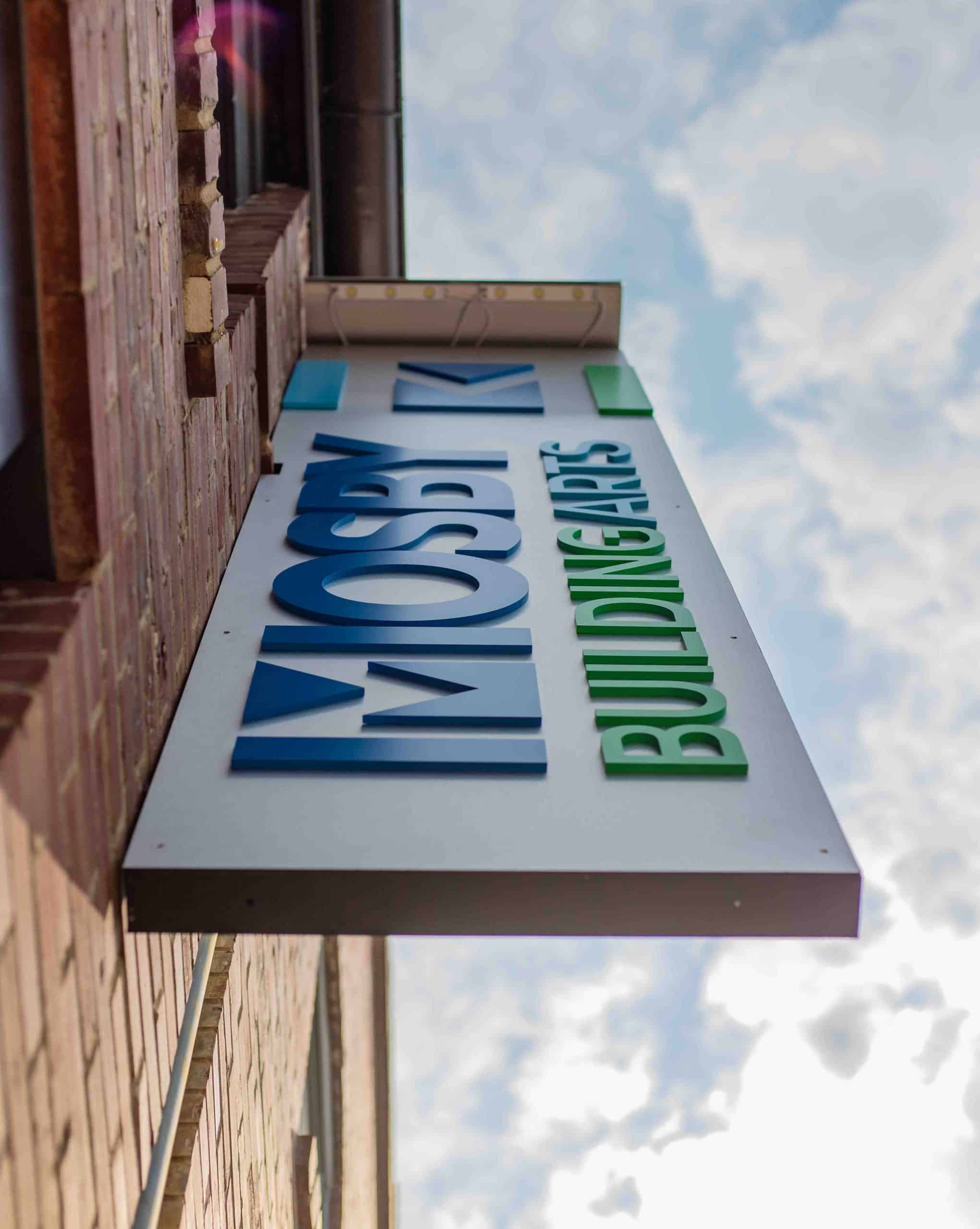 custom aluminum panel signage hung on brick building matching Mosby Building Arts branding