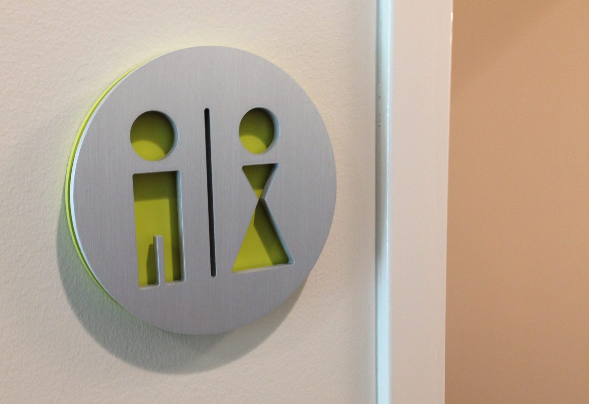 Dimensional circle restroom sign grey circle cut out with green shining through