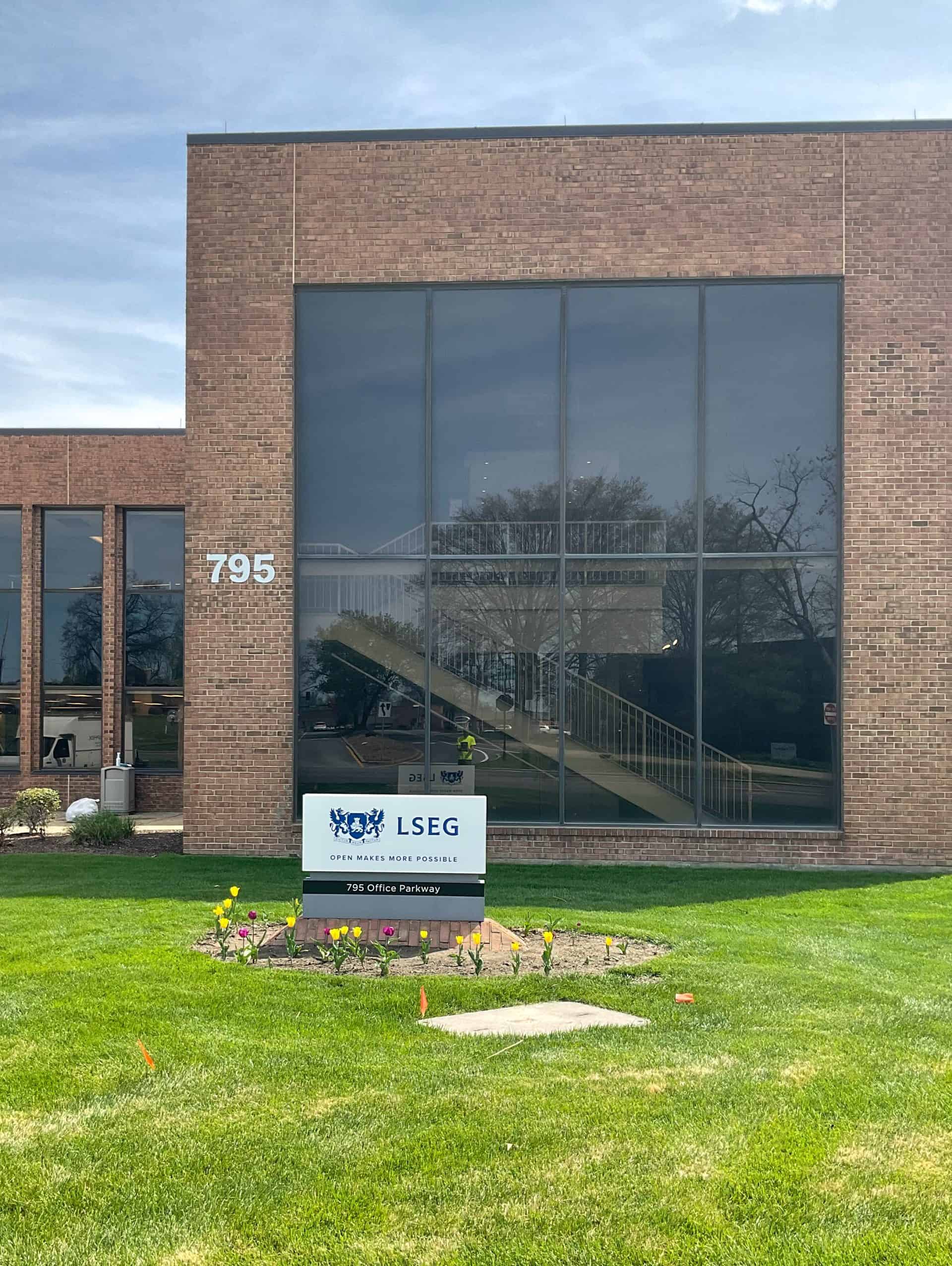 Exterior monument sign grey backing with blue LSEG quote in front of brown office building